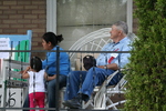 Woman, child, man sitting on porch by Julie Berg-Raymond